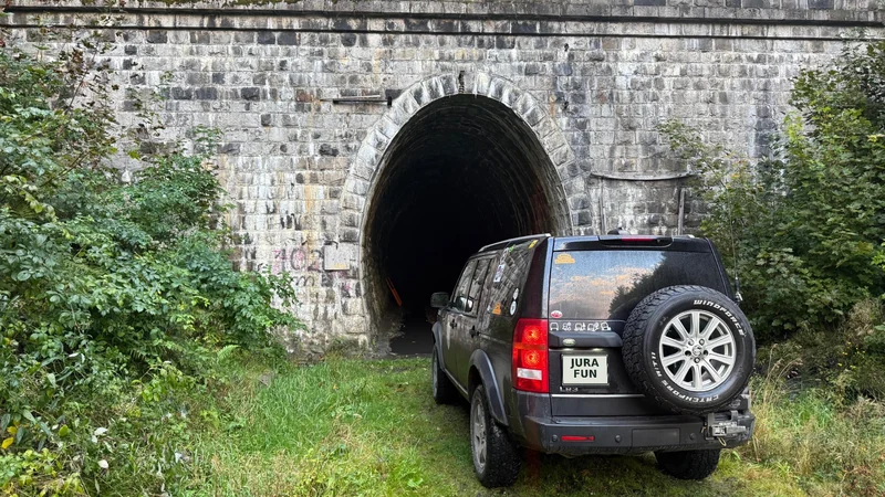 Discovery 3 przy kamiennym tunelu; tablica zastąpiona napisem JuraFun